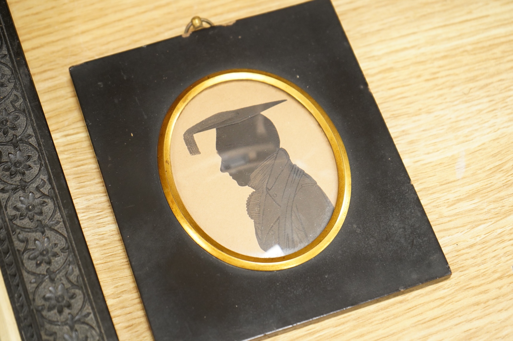 Early 19th century, English School, Cut paper silhouette portrait of a young man in academic robes and mortar board, together with two other silhouette portraits, with inscriptions verso, to include Reverend Lowry Guthri